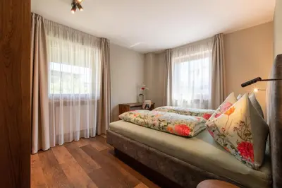 a bedroom with a bed and two windows at Apartments Karbon in Castelrotto