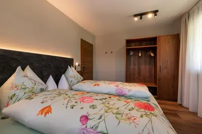 a bedroom with a bed with a floral bedspread at Apartments Karbon in Castelrotto