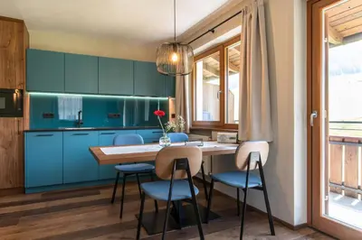 a kitchen with blue cabinets and a wooden table and chairs at Apartments Karbon in Castelrotto