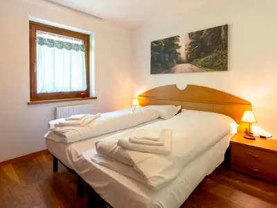 a bedroom with two beds with white sheets at Apartment Ca' di nonón by Interhome in Penia