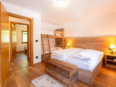 a bedroom with a bed with a wooden wall at Apartment Ca' di nonón by Interhome in Penia