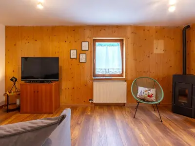 a living room with a television and a chair at Apartment Ca' di nonón by Interhome in Penia