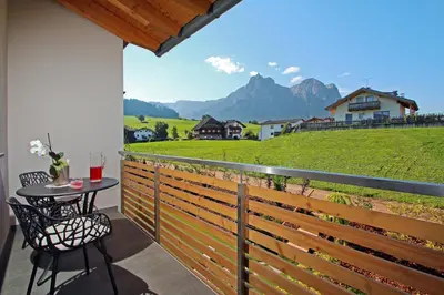 a house with a view of a garden with two chairs at Apartments Cornelia in Castelrotto