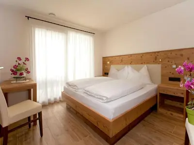 a bedroom with a bed with red sheets and a window at Apartments Cornelia in Castelrotto