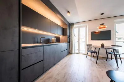 a kitchen with black cabinets and a table with chairs at ANDERS City Loft in Brunico