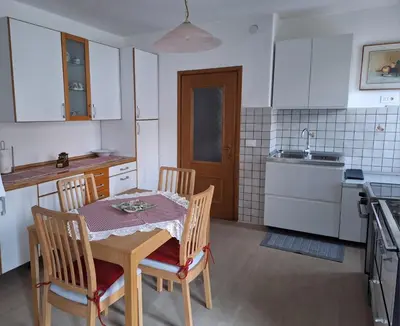 a kitchen with a table and chairs and a kitchen with white cabinets at Appartamento Medán in Mezzano