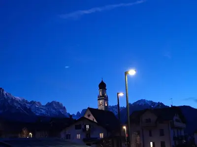 a building with a clock tower at night with mountains at Appartamento Medán in Mezzano