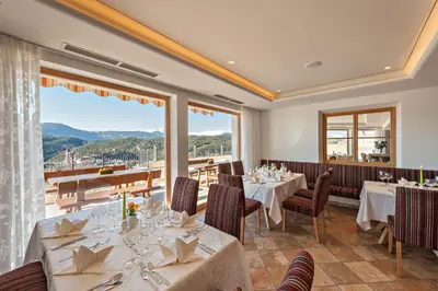 a restaurant with tables and chairs and a large window at Hotel Rosslaufhof in Castelrotto