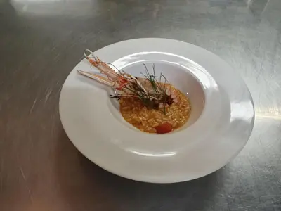 a white plate with a bowl of food on a table at Hotel Rosslaufhof in Castelrotto