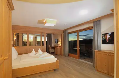 a hotel room with a bed and a desk and window at Hotel Rosslaufhof in Castelrotto