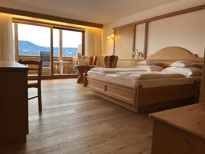 a bedroom with a bed and a large window at Hotel Rosslaufhof in Castelrotto