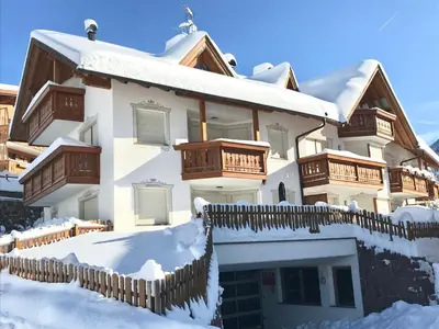 a house covered in snow with a fence at Romys Apartment in Selva di Val Gardena