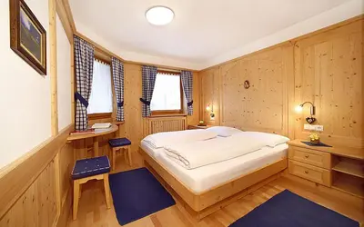 a bedroom with a large white bed and wooden walls at Romys Apartment in Selva di Val Gardena