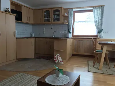 a kitchen with wooden cabinets and a table and a window at Romys Apartment in Selva di Val Gardena