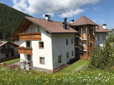 a large white house with wooden balconies at Romys Apartment in Selva di Val Gardena