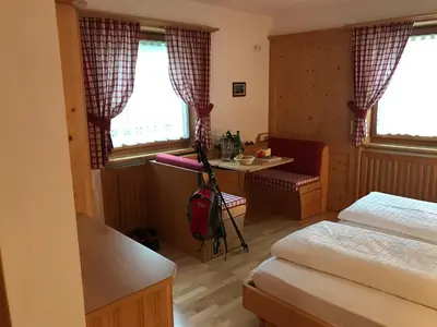 a room with two beds and a desk with a red backpack at Romys Apartment in Selva di Val Gardena