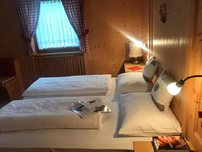 a bedroom with two beds and a lamp and a window at Romys Apartment in Selva di Val Gardena
