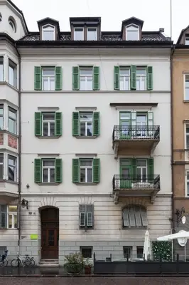 a tall white building with green shuttered windows at Stay COOPER l Laurenz in Bolzano