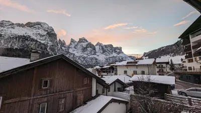 a village with snow covered buildings and mountains at Garni Diamant in Colfosco
