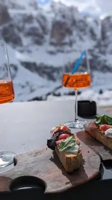 a table with two sandwiches and a glass of wine at Garni Diamant in Colfosco