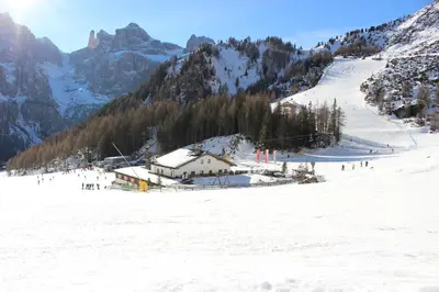 a snow covered mountain with a ski lodge on a ski slope at Garni Diamant in Colfosco