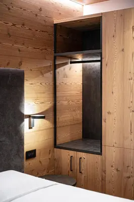 a bedroom with a wooden wall with a mirror at Le Fronde - Naturally Smart in Cles