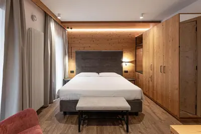 a bedroom with a large bed and a chair at Le Fronde - Naturally Smart in Cles