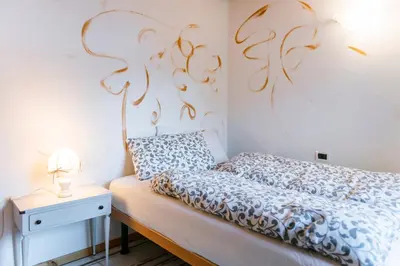 a small bedroom with a bed and a nightstand with a lamp at Ciasa Buro - Resh in Moena