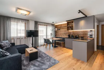a living room with a couch and a kitchen at Chalet Lumis in San Vigilio Di Marebbe