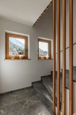 a room with a staircase and two windows at Chalet Lumis in San Vigilio Di Marebbe