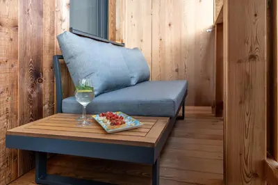 a blue couch with a table and a glass of wine at La Munt in Longega