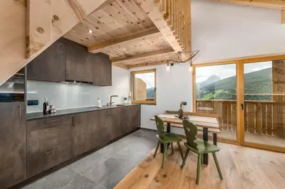 a kitchen with a wooden table and green chairs at La Munt in Longega