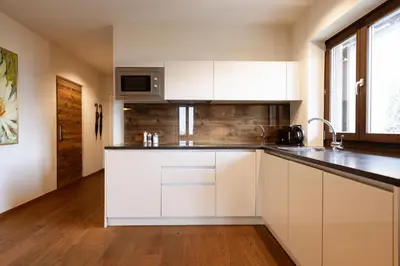 a kitchen with white cabinets and black counter tops at Stöckler Hof in Lana