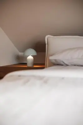 a white bed with a lamp on a table at Stöckler Hof in Lana
