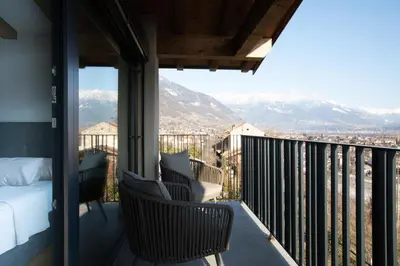 a balcony with a bed and chairs and mountains at Stöckler Hof in Lana