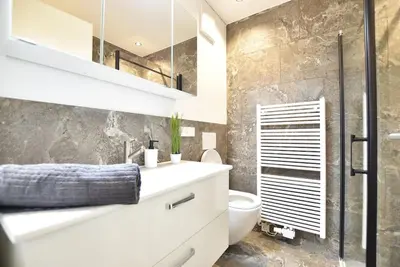 a bathroom with a white sink and a toilet at Cosy new apartment in calm area near merano in Merano