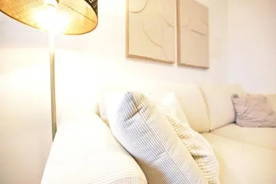 a living room with a white couch and a floor lamp at Cosy new apartment in calm area near merano in Merano