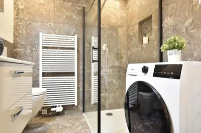 a bathroom with a toilet and a washing machine at Cosy new apartment in calm area near merano in Merano