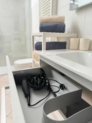 a bathroom with a black hair dryer in a drawer at Öhlers Prime Suite in Vipiteno