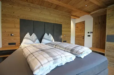 a bedroom with a large bed with wooden walls at Chalet Roderer in Laion