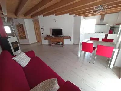 a living room with a red couch and a table at Appartamento Lorena a Mezzano in Mezzano