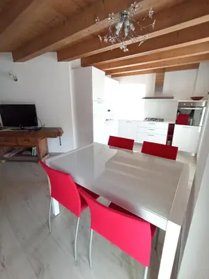 a dining room with a white table and red chairs at Appartamento Lorena a Mezzano in Mezzano