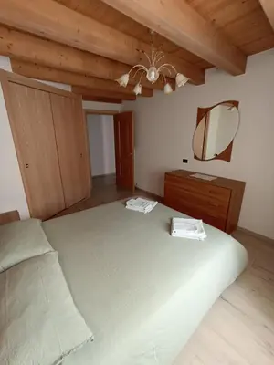 a bedroom with a large bed and a mirror at Appartamento Lorena a Mezzano in Mezzano