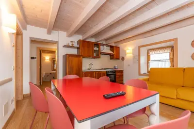 a kitchen and dining room with a red table and chairs at Casa Alessandra in Falcade