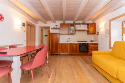 a kitchen and living room with a table and a yellow couch at Casa Alessandra in Falcade