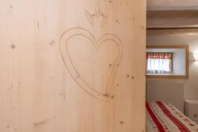 a heart carved on the wall of a bedroom at Casa Alessandra in Falcade