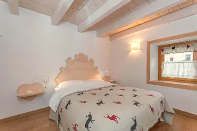a bedroom with a bed with a comforter and a window at Casa Alessandra in Falcade