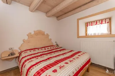a bedroom with a bed with a red and white blanket at Casa Alessandra in Falcade