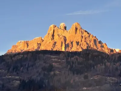 a large rocky mountain with trees in front of it at Casa Dolomiti in Mezzano