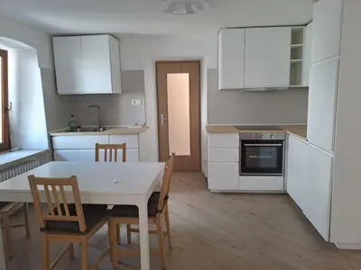 a kitchen with white cabinets and a table and chairs at Casa Dolomiti in Mezzano